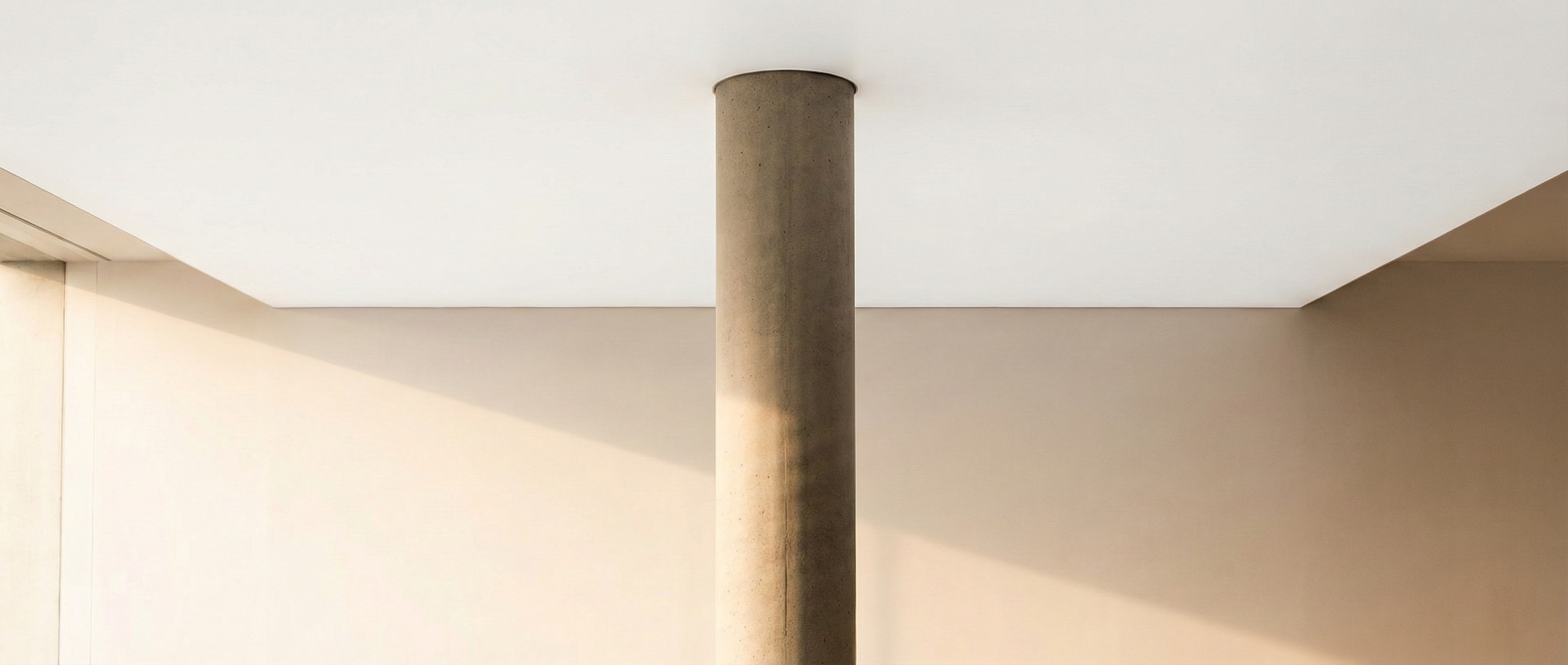 Single concrete pillar supporting a vast clean ceiling — monolithic, structural, powerful